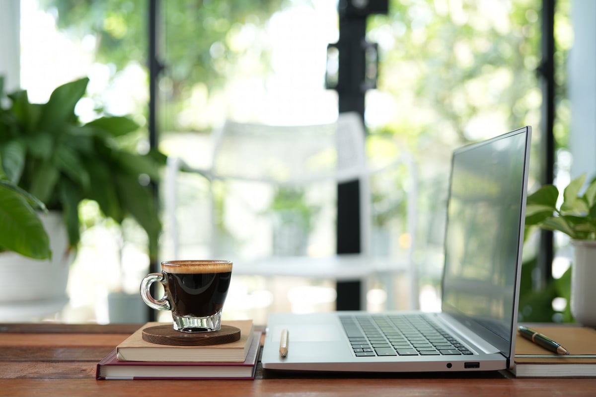 Coffee and laptop on rustic wood table — Kelley's writing setup