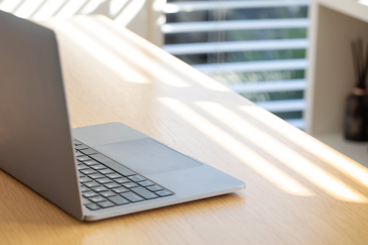 Minimalist home office workspace with open laptop in sunlit room, clean and uncluttered
