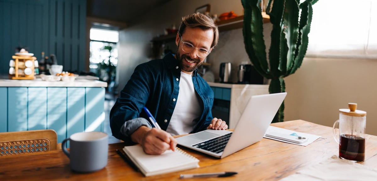 Man working from home at a bright living space desk near plants