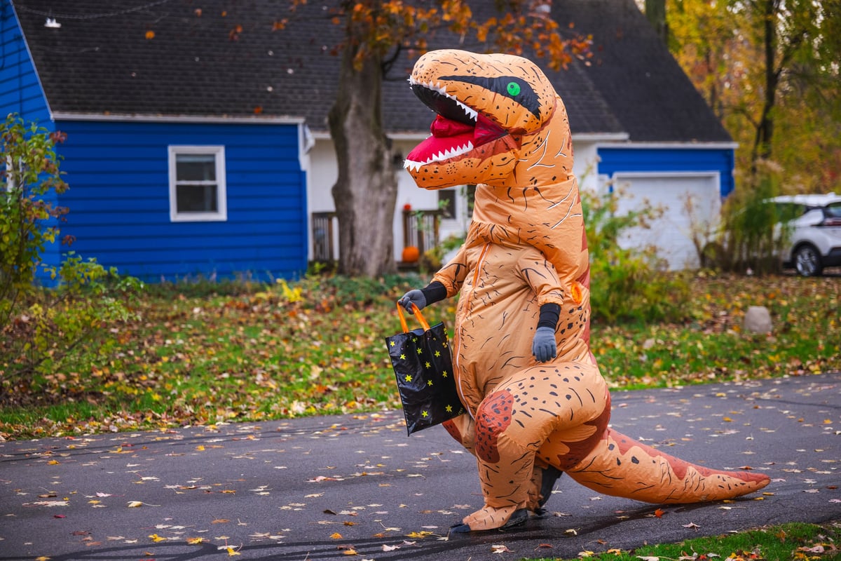 Person in inflatable dinosaur costume on suburban street