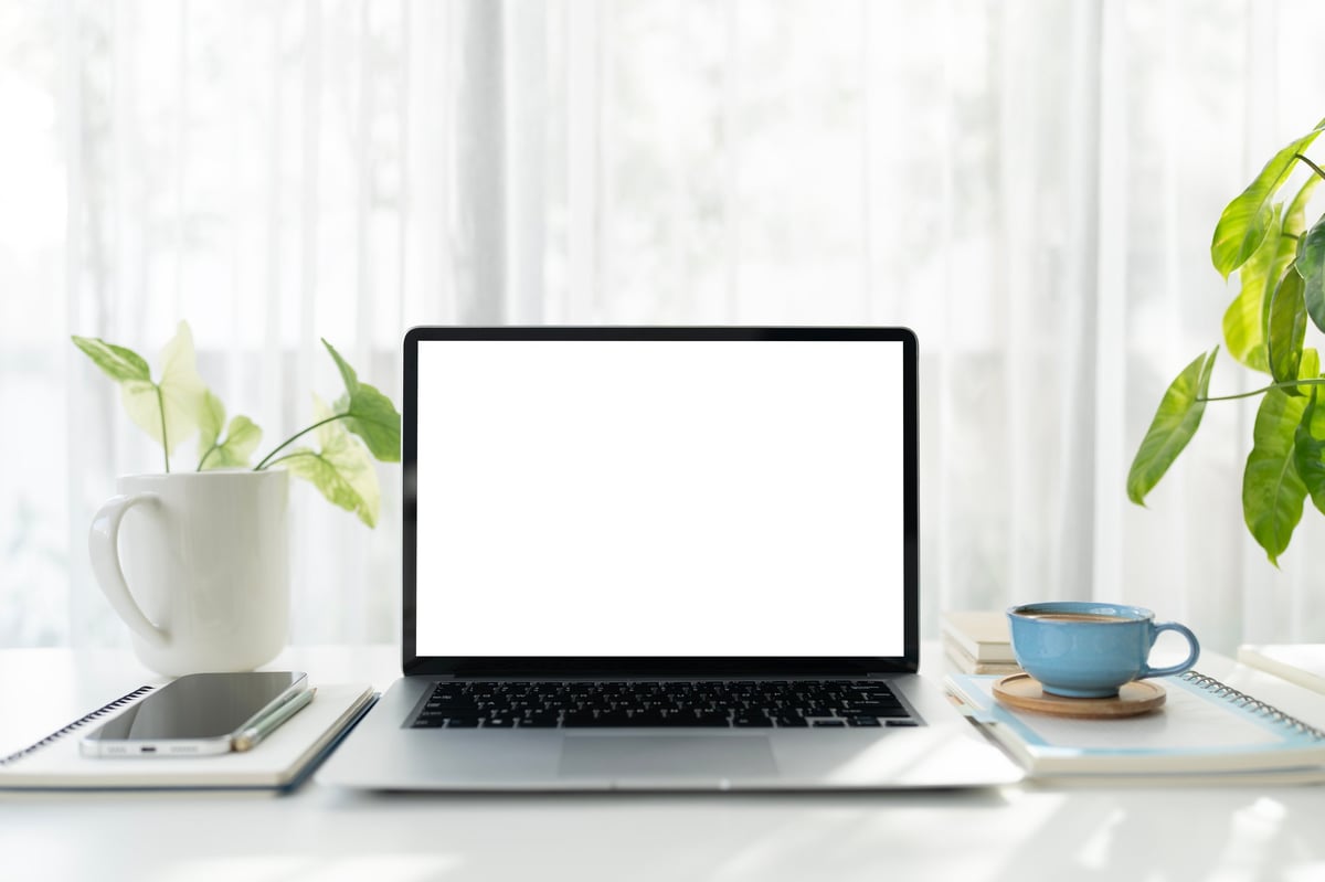 Laptop on a cozy desk with coffee and plants — a warm modern work-from-home setup