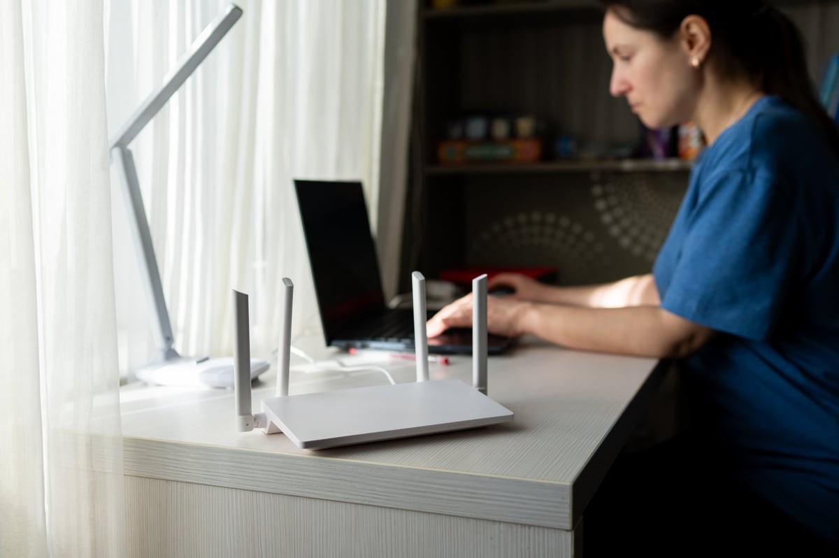 Modern WiFi router on desk with person working in background