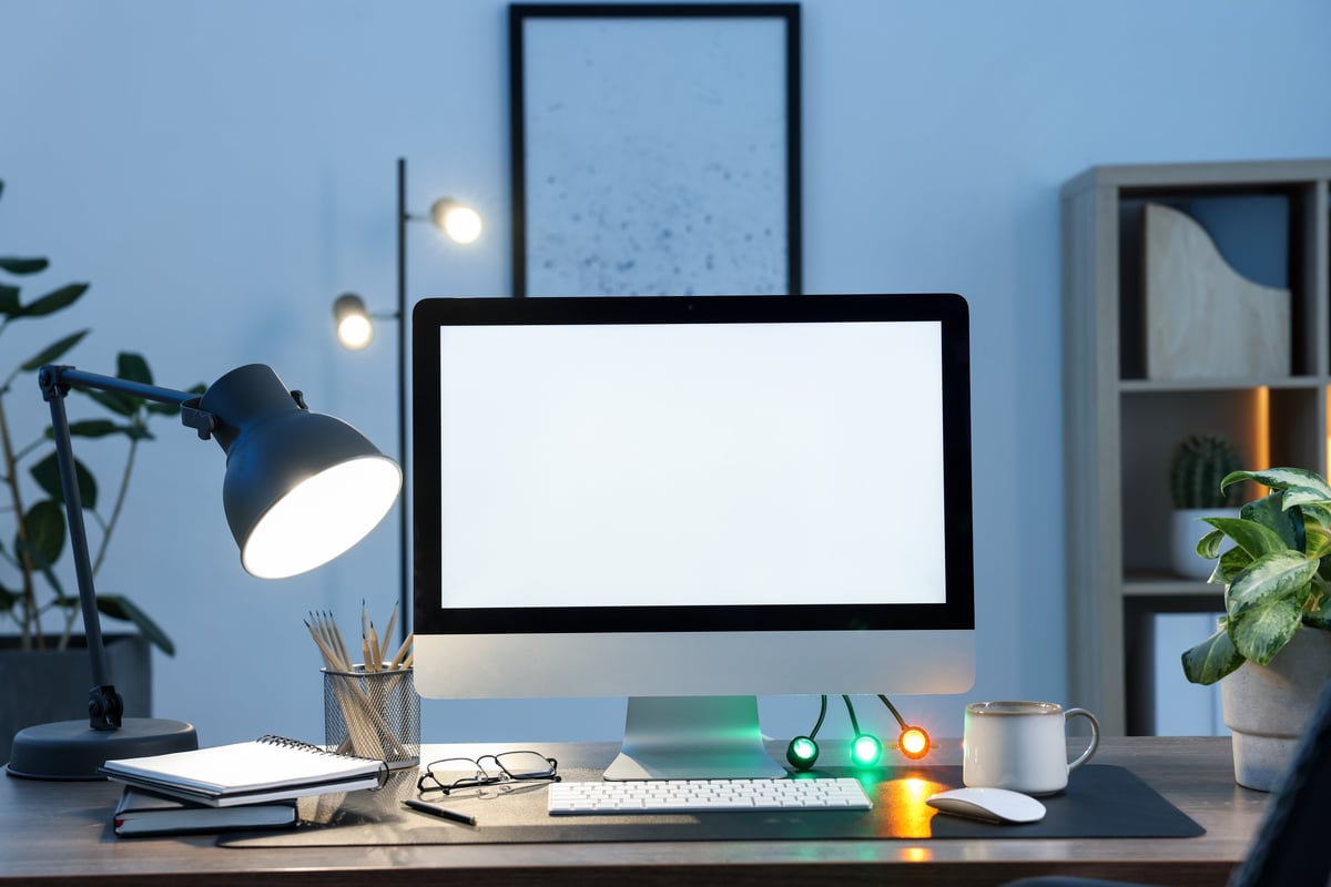 Stylish modern desk workspace with warm lamp lighting on wooden desk